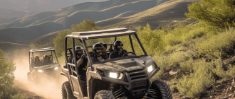 A photograph of a camouflage-colored 5-seater side-by-side UTV driving down a dusty trail in the mountains.